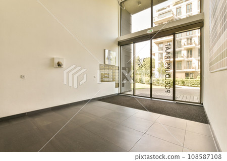 an empty room with glass doors and black tiles on the floor, in front of a large white brick wall 108587108
