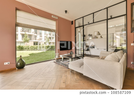 a living room with pink walls and wood flooring in the center of the room, there is a tv on the wall a living room with pink walls and wood flooring in the center of the room, there is a tv on the wall 108587109