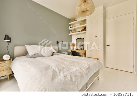 a bedroom with a bed, dresser and lamp on the wall behind it is an open white door that leads to another room a bedroom with a bed, dresser and lamp on the wall behind it is an open white door that leads to another room 108587113