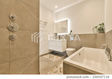 a bathroom with a sink, toilet and mirror in the corner next to the bathtub that has been installed on the wall a bathroom with a sink, toilet and mirror in the corner next to the bathtub that has been installed on the wall 108587116