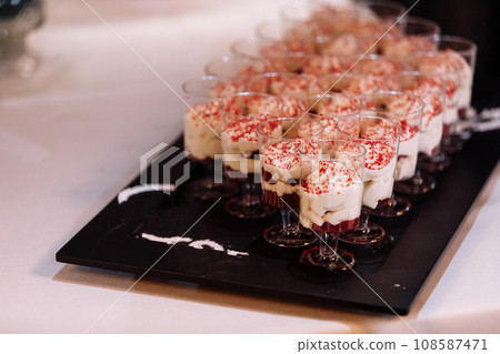 Trifle red velvet with cream cheese cream and cherry gels in glass cup. Sweet homemade Parfait dessert with whipped cream. candy bar on birthday party, wedding. Trifle red velvet with cream cheese cream and cherry gels in glass cup. Sweet homemade Parfait dessert with whipped cream. candy bar on birthday party, wedding. 108587471