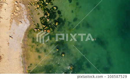 Dead Sea coastline in desert uninhabited extraterrestrial landscape aerial view. girl swims on the sea. lonely swimmer. Dead Sea coastline in desert uninhabited extraterrestrial landscape aerial view. girl swims on the sea. lonely swimmer. 108587529