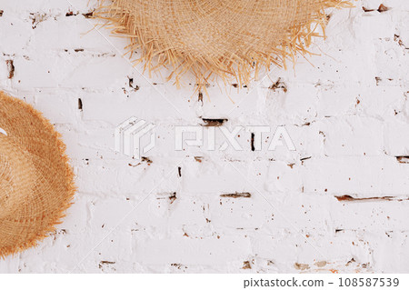 a straw hat on a background of a white brick wall with copy space. Travel concept 108587539