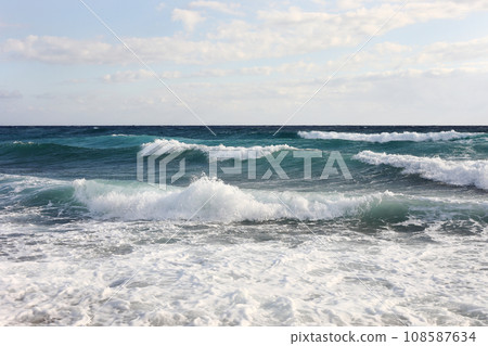 sea waves on the surface of sea water during strong winds and bad weather, sunny day, sky with clouds. sea waves on the surface of sea water during strong winds and bad weather, sunny day, sky with clouds. 108587634
