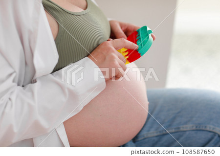pregnant woman with big belly advanced pregnancy is using anti stress toy poppit and sitting on chair at home. anxiety and nervousness before childbirth. Healthy pregnancy and happy maternity. 108587650