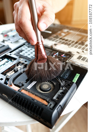 Repaiman with brush is cleaning disassembled laptop parts. Technical support and fixing gadgets problems. Servicing, repairing, cleaning, maintaining computers. Repair shop. Hardware maintenance. Repaiman with brush is cleaning disassembled laptop parts. Technical support and fixing gadgets problems. Servicing, repairing, cleaning, maintaining computers. Repair shop. Hardware maintenance. 108587772