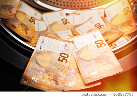 Money laundering symbol, 50 euro banknotes inside washing machine. Tax evasion. Illegal financial transactions. Euro currency Money laundering symbol, 50 euro banknotes inside washing machine. Tax evasion. Illegal financial transactions. Euro currency 108587795