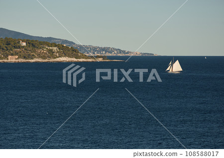 Monaco, huge sail yacht is in sea at sunset, island is nearby, wealth life of billionaires, mountains on background Monaco, huge sail yacht is in sea at sunset, island is nearby, wealth life of billionaires, mountains on background 108588017