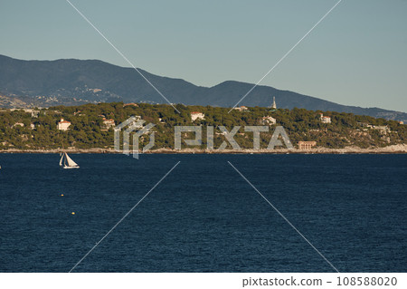 Monaco, huge sail yacht is in sea at sunset, island is nearby, wealth life of billionaires, mountains on background Monaco, huge sail yacht is in sea at sunset, island is nearby, wealth life of billionaires, mountains on background 108588020