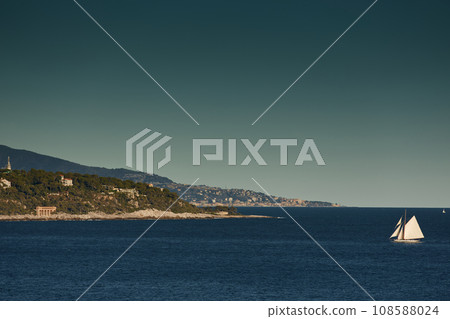 Monaco, huge sail yacht is in sea at sunset, island is nearby, wealth life of billionaires, mountains on background Monaco, huge sail yacht is in sea at sunset, island is nearby, wealth life of billionaires, mountains on background 108588024