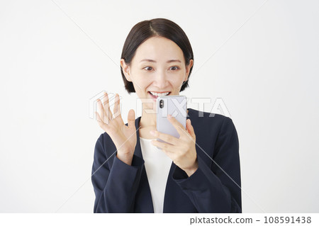 Surprised middle-aged business woman holding a smartphone and smiling, white background Surprised middle-aged business woman holding a smartphone and smiling, white background 108591438