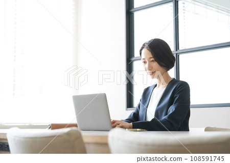 A woman in her 30s in a suit working in an office 108591745