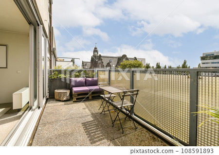 an outside area with a table, chairs and bench on the left side of the patio looking out onto the street an outside area with a table, chairs and bench on the left side of the patio looking out onto the street 108591893