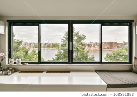 a window with a view of the water and buildings in the distance, as seen from an empty office space 108591898