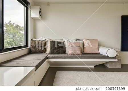 a window seat in the corner of a room with white carpet and pillows on it's windowsills 108591899