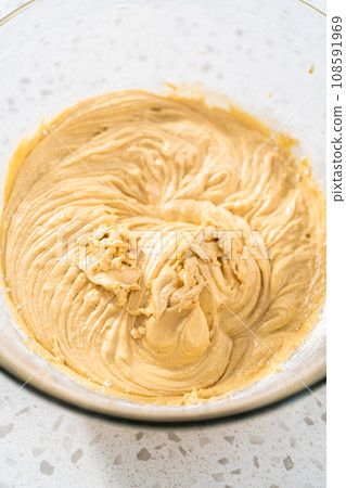 Mixing ingredients with a hand mixer in a large mixing bowl to bake dulce de leche cupcakes. 108591969