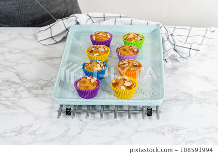 Freshly baked lemon poppy seed muffins garnished with almond slivers on the kitchen counter. 108591994