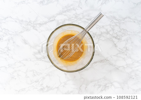 Flat lay. Mixing wet ingredients in a large glass mixing bowl to bake lemon poppy seed muffins. 108592121