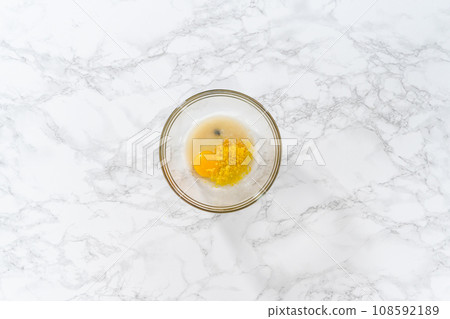 Lemon Cookies with White Chocolate. Flat lay. Mixing wet ingredients in a large glass mixing bowl to bake lemon cookies with white chocolate. 108592189