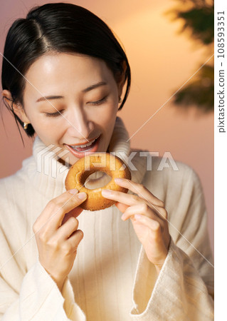 Woman in her 30s eating a donut 108593351