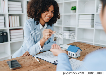 Female African american Real estate company to buy houses and land are delivering keys and houses to customers after agreeing to make a home purchase agreement and make a loan agreement 108594009