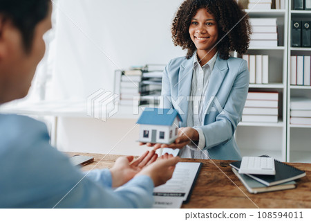 Female African american Real estate company to buy houses and land are delivering keys and houses to customers after agreeing to make a home purchase agreement and make a loan agreement 108594011