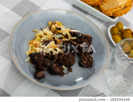 Spanish blood sausage morcilla served with grilled onion 108594166