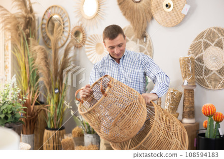 Male shopper in furniture center chooses new wicker laundry basket Male shopper in furniture center chooses new wicker laundry basket 108594183