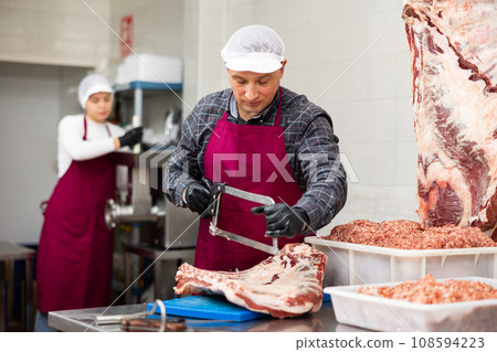 Adult male butcher sawing beef ribs Adult male butcher sawing beef ribs 108594223