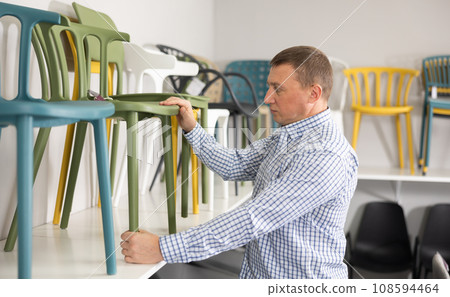 In furniture store, man considering choose chairs for completing office suite 108594464