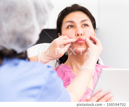 Doctor beautician discussing with woman cosmetological procedure Doctor beautician discussing with woman cosmetological procedure 108594702