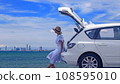 Woman relaxing inside the white hatchback car trunk at the beach and watching to the blue sea with blue sky and white cloud background. Traveler car concept. 108595010