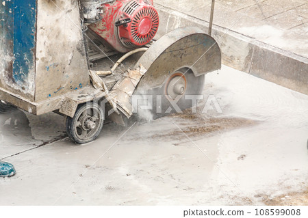 Worker using diamond saw blade machine cutting concrete road at construction site Worker using diamond saw blade machine cutting concrete road at construction site 108599008