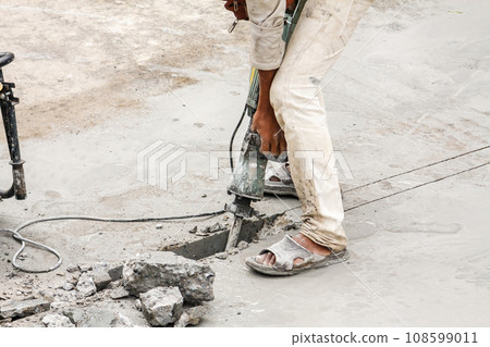 Construction worker using jackhammer drilling concrete surface Construction worker using jackhammer drilling concrete surface 108599011