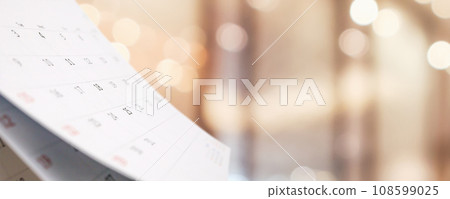 Close up white paper desk calendar with blurred bokeh background appointment and business meeting concept Close up white paper desk calendar with blurred bokeh background appointment and business meeting concept 108599025