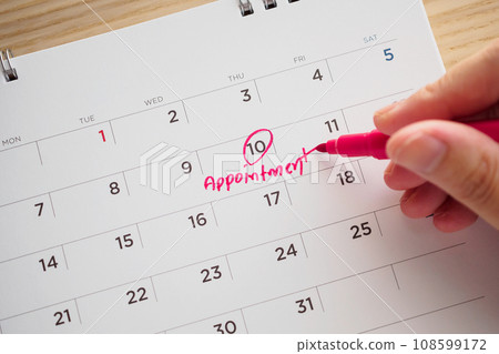 Hand with pen writing on calendar date appointment concept 108599172
