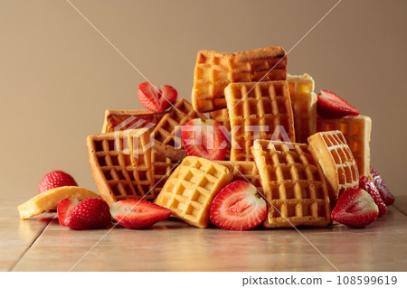 Belgian waffles with strawberries on a beige background. Belgian waffles with strawberries on a beige background. 108599619