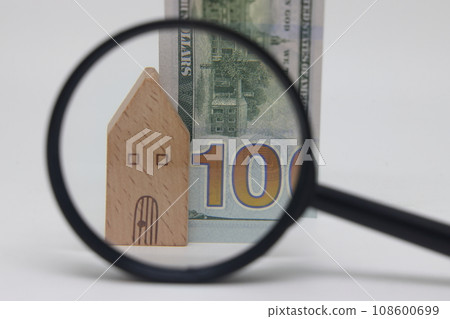 View of a house and a banknote through a magnifying glass, real estate purchase and insurance 108600699