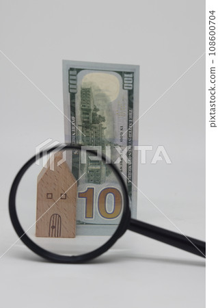 View of a house and a banknote through a magnifying glass, real estate purchase and insurance 108600704