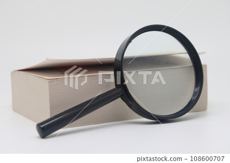 Opening book macro with magnifying glass on a white background. 108600707