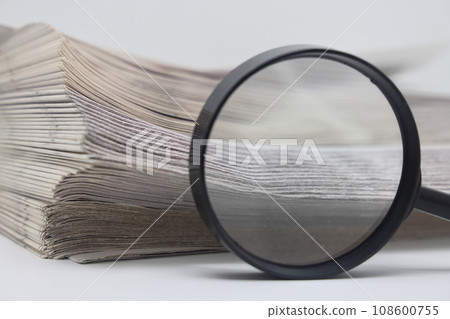 magnifier on the background of the stack of magazines. magnifier on the background of the stack of magazines. 108600755