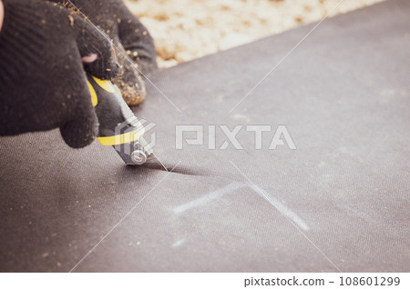 A man cuts a black agricultural fiber along the label A man cuts a black agricultural fiber along the label 108601299