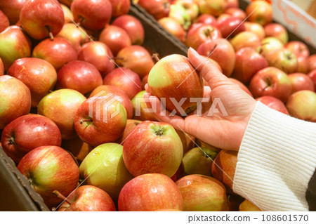 hand taking apple from grocery store shelf hand taking apple from grocery store shelf 108601570