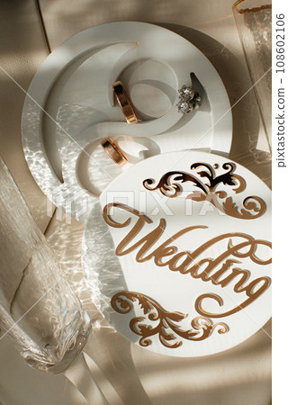 Wedding rings on a wooden box with shadows of leaves Wedding rings on a wooden box with shadows of leaves 108602106