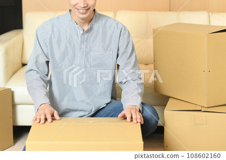 An Asian man cleaning up in front of a large number of cardboard boxes 108602160