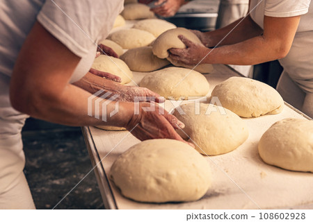 Bakers forming bread dough in a bakery Bakers forming bread dough in a bakery 108602928
