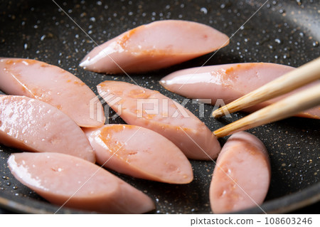 A cooking scene where fish sausage (diagonally cut) is stir-fried in a frying pan. 108603246