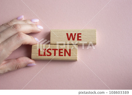 We listen symbol. Wooden blocks with words We listen. Businessman hand. Beautiful pink background. Business and We listen concept. Copy space. We listen symbol. Wooden blocks with words We listen. Businessman hand. Beautiful pink background. Business and We listen concept. Copy space. 108603389