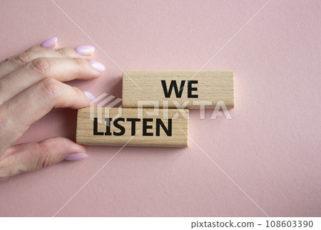 We listen symbol. Wooden blocks with words We listen. Businessman hand. Beautiful pink background. Business and We listen concept. Copy space. We listen symbol. Wooden blocks with words We listen. Businessman hand. Beautiful pink background. Business and We listen concept. Copy space. 108603390