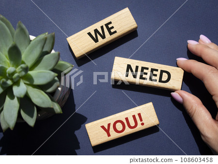 We need You symbol. Wooden blocks with words We need you. Beautiful deep blue background with succulent plant. Businessman hand. Business and We need You concept. Copy space 108603458